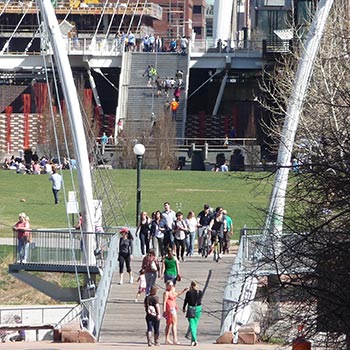 Restoring a walkable city: pedestrians on Denver's Highland Bridge over the South Platte River northwest of LoDo. Background: Commons Park and the Millennium Bridge. Photo by Ken Schroeppel.