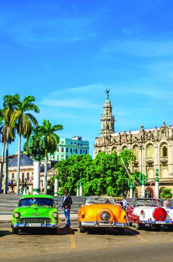 HAVANA, CUBA - DECEMBER 2, 2013: Classic American colorful cars one of streets in Havana, where old cars bought before Cuban revolution are icon view of Cuba
