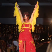 a model poses flamboyantly on the Condom Couture runway in a high-low dress made of condoms