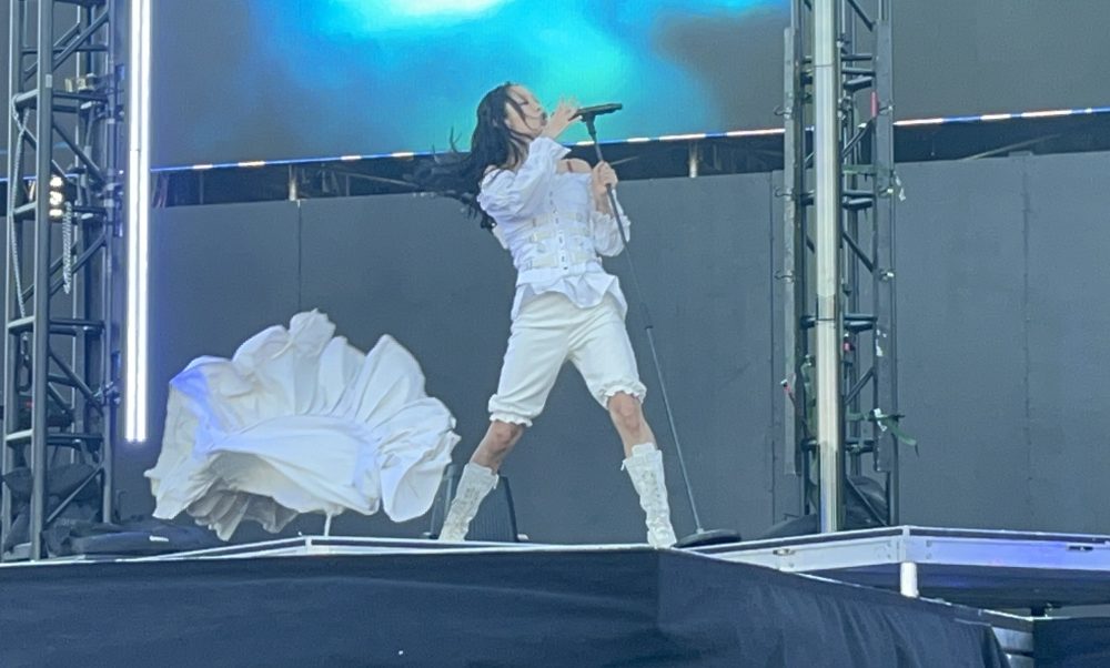 Portola Festival artist Rina Sawayama at the mic doing one of her signature back bends