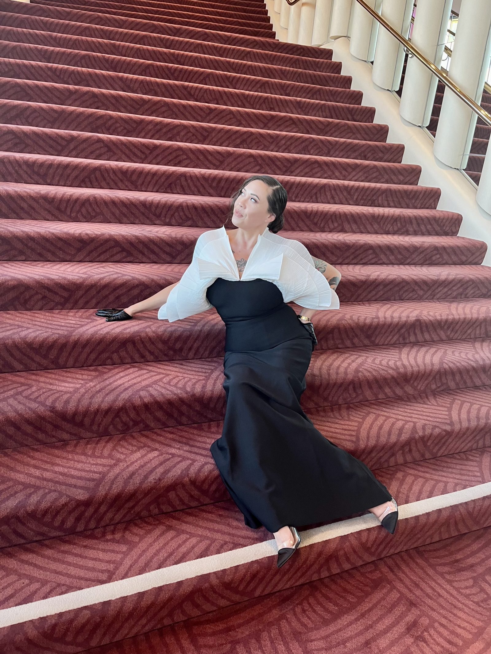 The author of the piece wearing an avant garde black and white gown, sitting on a staircase