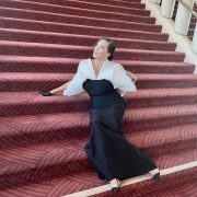 The author of the piece wearing an avant garde black and white gown, sitting on a staircase