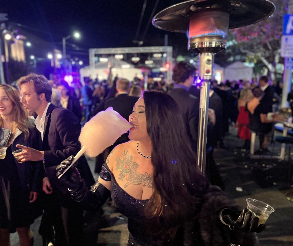 Rose Eden in dress with long gloves, biting into cotton candy