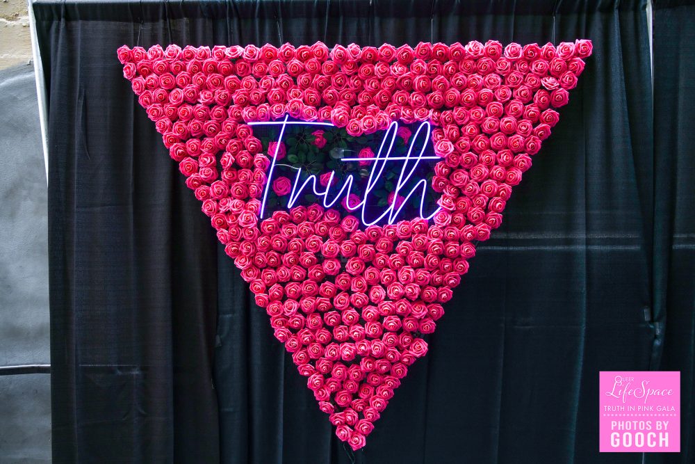 The Truth in Pink Gala v shaped step and repeat display, with a neon "Truth" sign in the middle of it, made all of hot pink roses