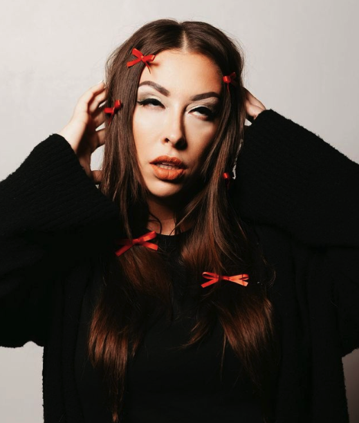 A retro, 60's mod style headshot of VNSSA rolling her eyes with multiple red bows clipped throughout her hair