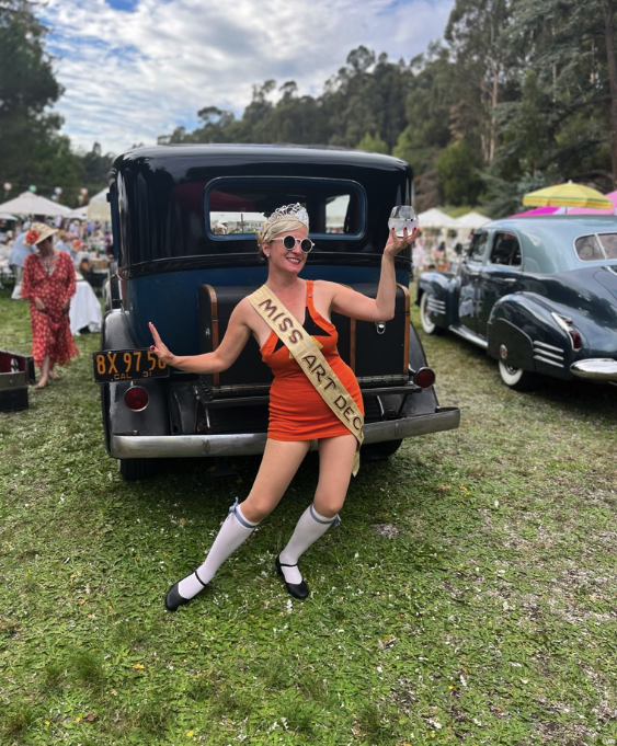 Miss Art Deco poses in front of vintage cars