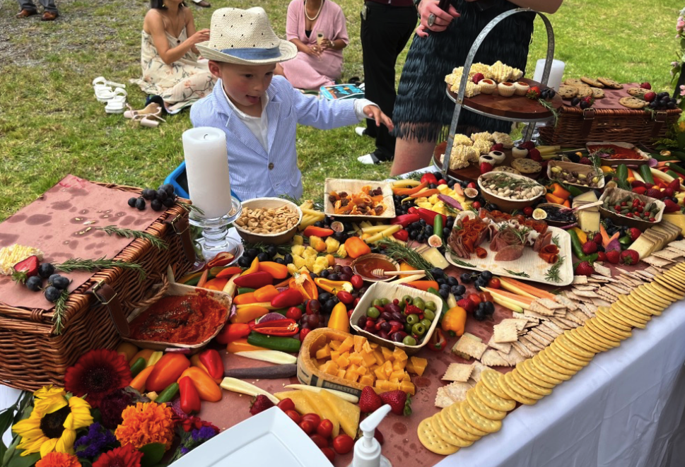an elaborate charcuterie table with a young boy grabbing for fruit