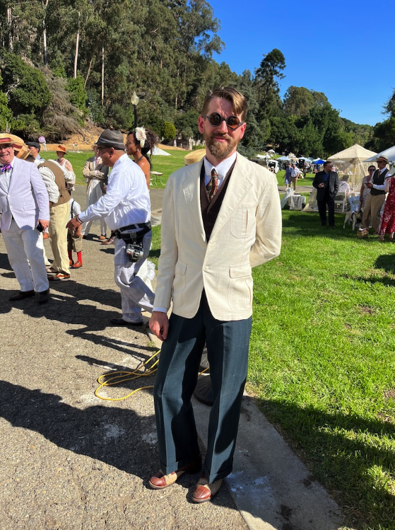 a dandy in a cream suit jacket and round sunglasses