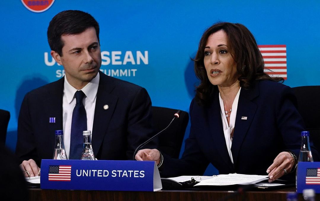 Pete Buttigieg, an option for Harris' VP, sits next to her in front of a blue screen
