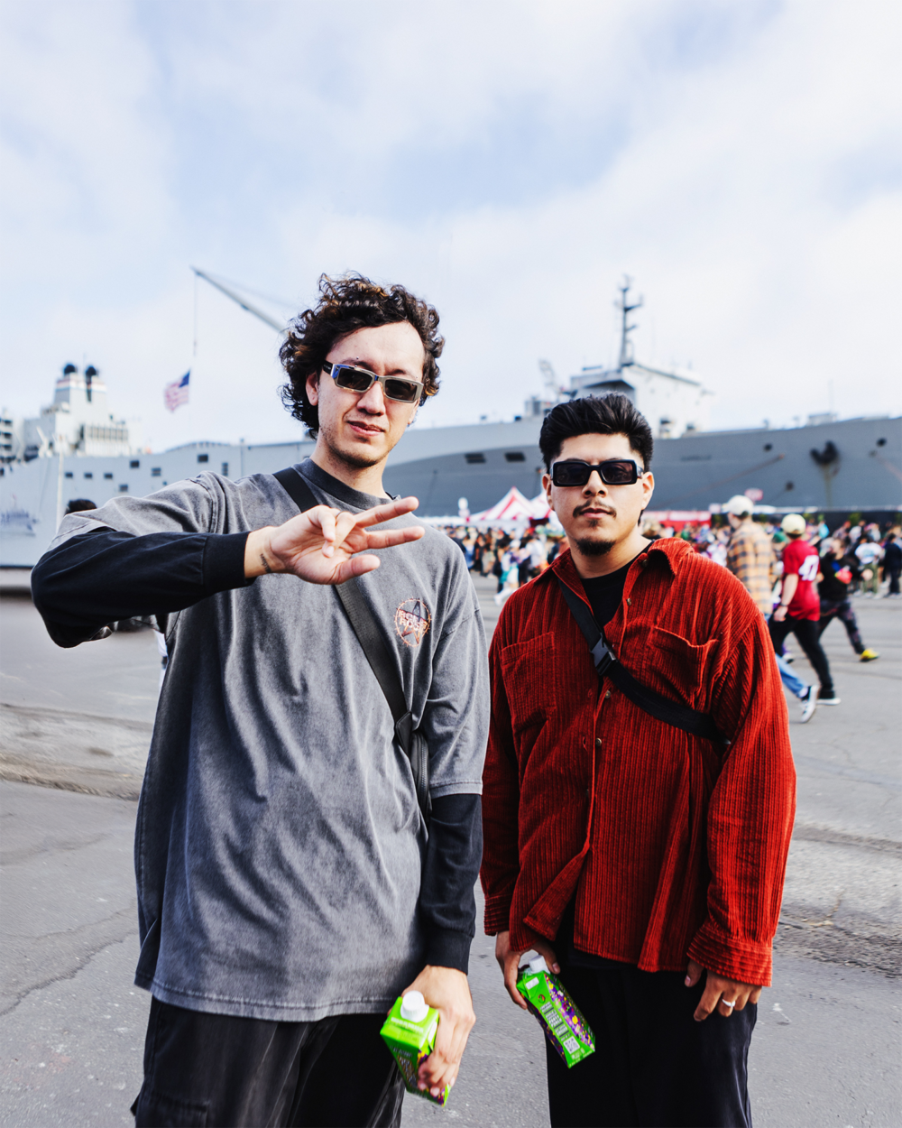 A festival goer throws up a peace sign with his friend beside him
