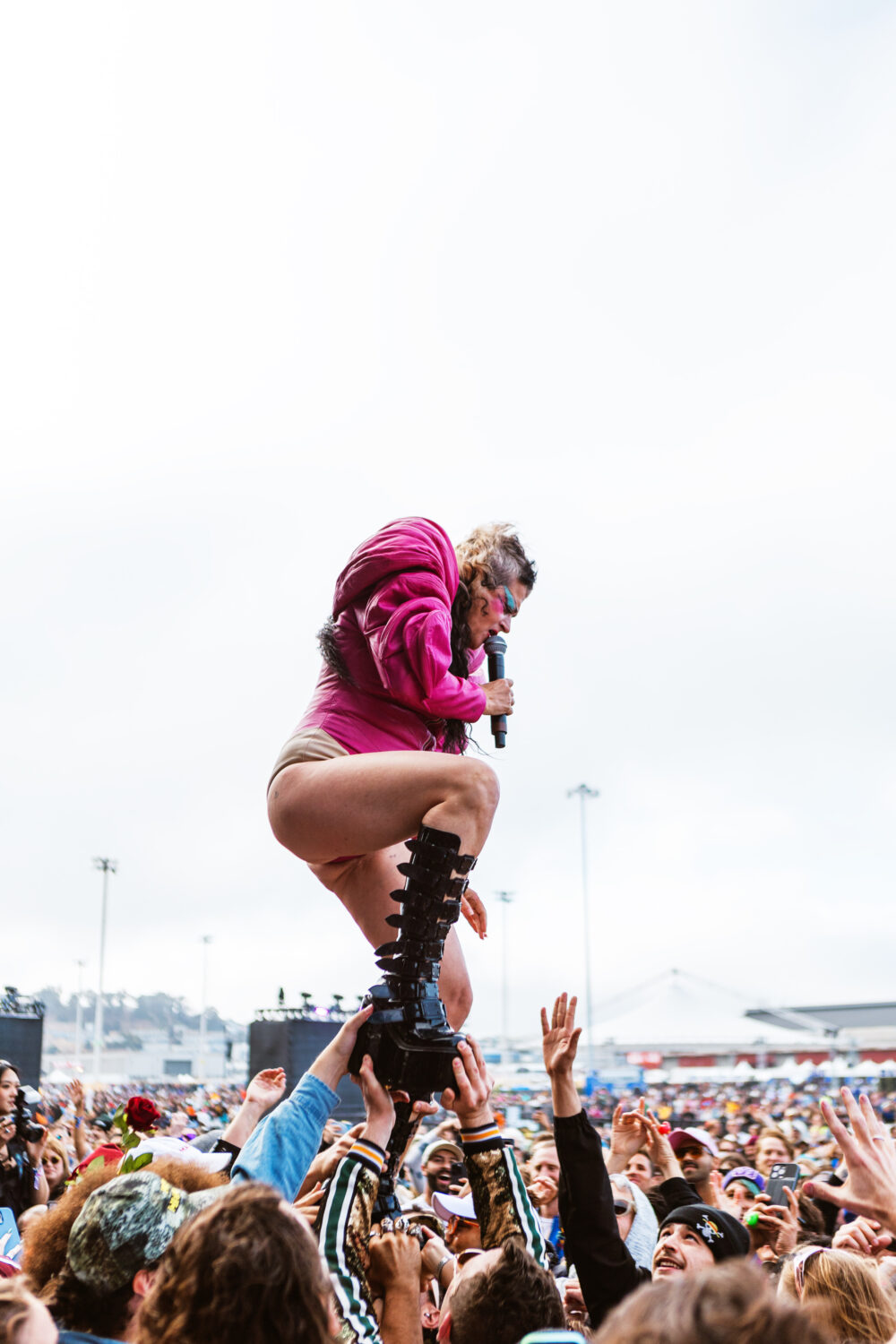 Peaches walks on top of the crowd with the audience supporting her and holding up her feet 