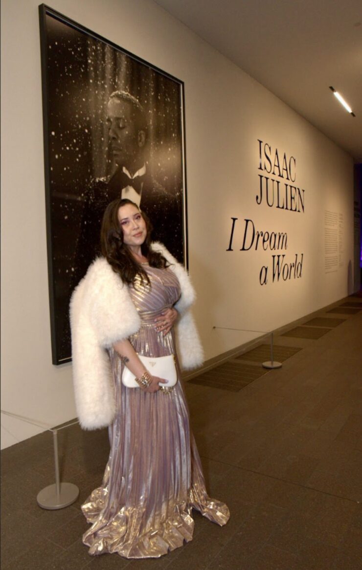 the author of the story poses at the entrance of the Sir Isaac Julien exhibit