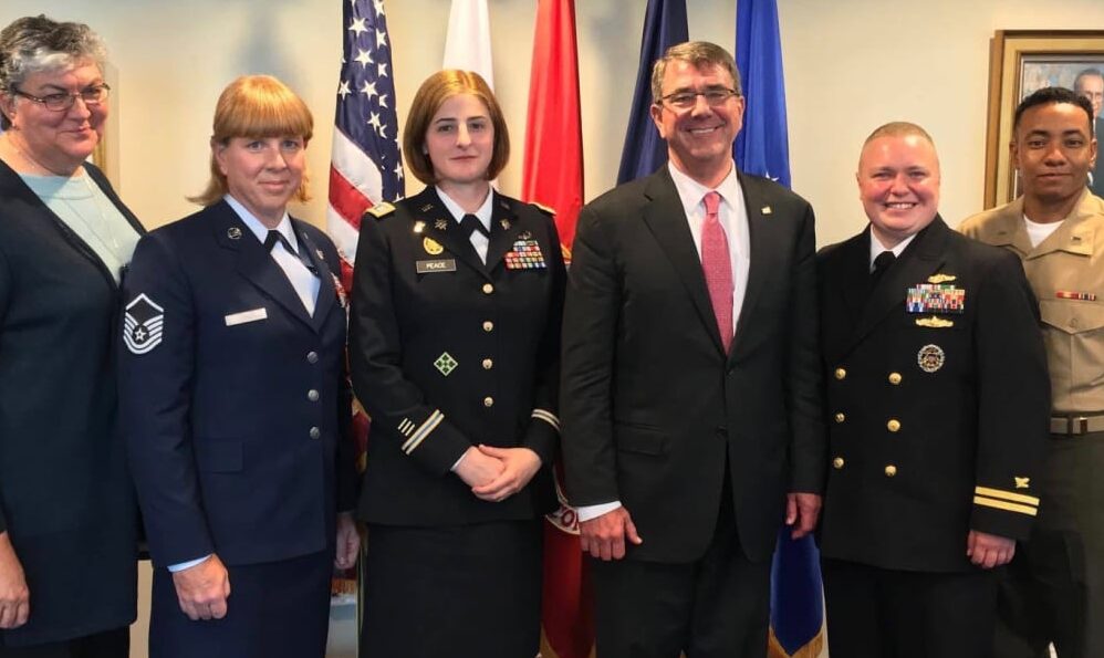 a group of trans military activists standing in front of court flags
